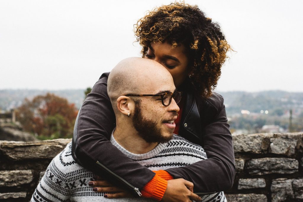 Woman in leather jacket hugs man from behind