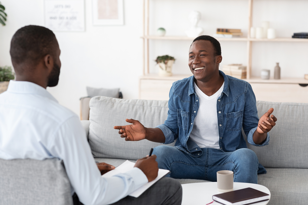 Successful Therapy. Cheerful black man talking to psychologist on meeting at his office