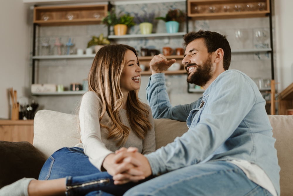 couple sitting on couch holding hands smiling